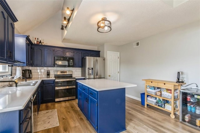 5309 NE Rainbow Cir, Lees Summit, MO 64064 - kitchen featuring stainless steel appliances, a sink, blue cabinetry, a center island, and tasteful backsplash