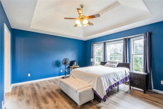5309 NE Rainbow Cir, Lees Summit, MO 64064 - bedroom featuring a tray ceiling, baseboards, wood finished floors, and a ceiling fan