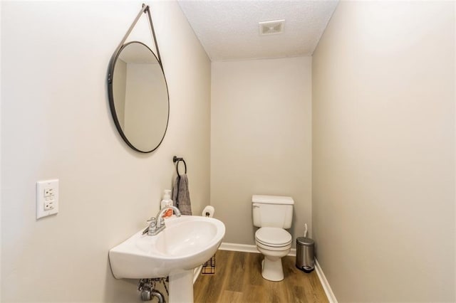 5309 NE Rainbow Cir, Lees Summit, MO 64064 - bathroom featuring wood finished floors, toilet, baseboards, a textured ceiling, and a sink