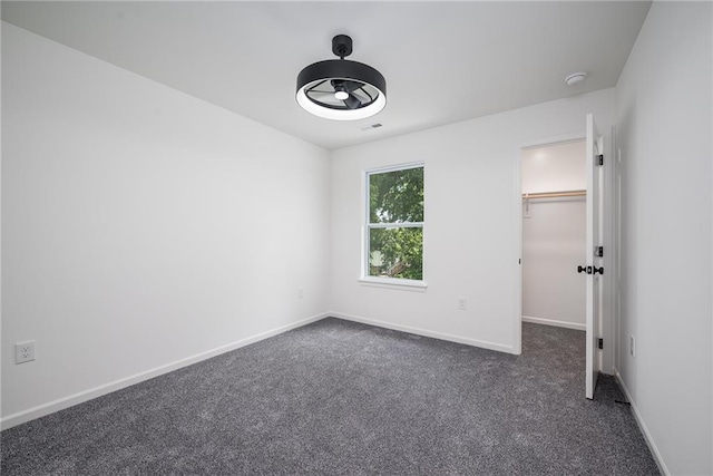 11147 Rowland Ave, Kansas City, KS 66109 - unfurnished bedroom with a spacious closet, baseboards, and dark colored carpet