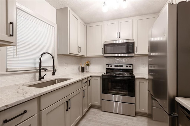 1617 N Pearl St, Independence, MO 64050 - kitchen featuring stainless steel appliances, decorative backsplash, light stone countertops, and a textured ceiling