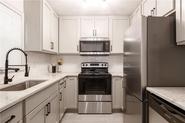 1617 N Pearl St, Independence, MO 64050 - kitchen featuring stainless steel appliances, decorative backsplash, and light stone countertops