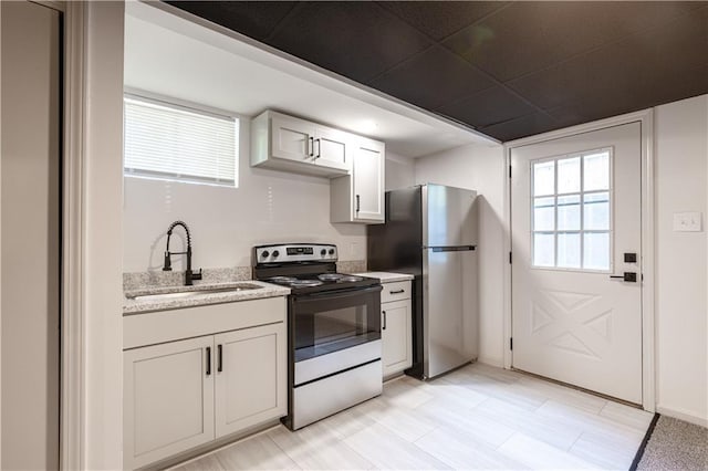 1617 N Pearl St, Independence, MO 64050 - kitchen with electric stove, freestanding refrigerator, white cabinets, and light stone countertops