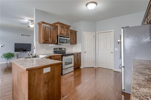 8905 NE 101st St, Kansas City, MO 64157 - kitchen featuring appliances with stainless steel finishes, a sink, light wood-style floors, ceiling fan, and a peninsula