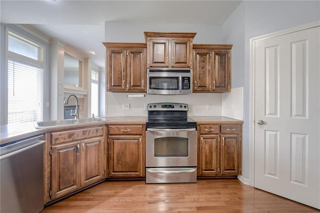 8905 NE 101st St, Kansas City, MO 64157 - kitchen with appliances with stainless steel finishes, a sink, decorative backsplash, light wood-type flooring, and light countertops