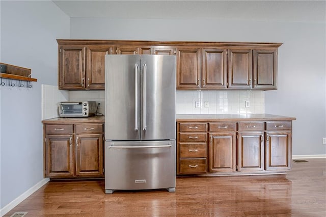 8905 NE 101st St, Kansas City, MO 64157 - kitchen featuring high quality fridge, decorative backsplash, light wood-type flooring, baseboards, and light countertops