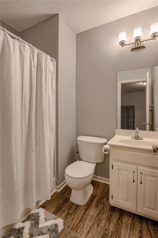 8905 NE 101st St, Kansas City, MO 64157 - full bathroom featuring wood finished floors, toilet, vanity, a textured ceiling, and baseboards