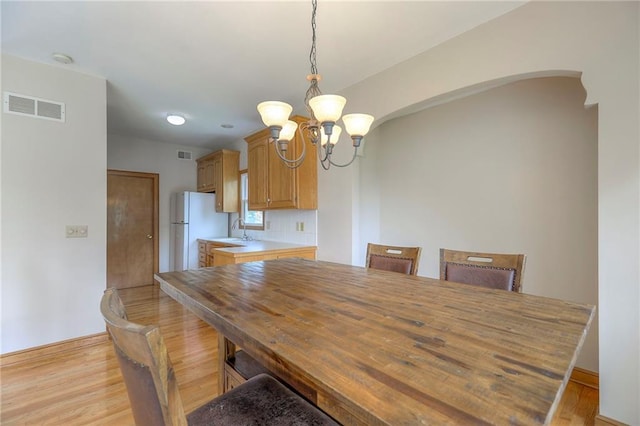 833 SW Harvest Dr, Grain Valley, MO 64029 - unfurnished dining area featuring a chandelier, light wood-style floors, arched walkways, and a sink