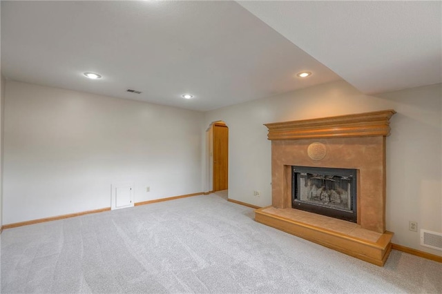 833 SW Harvest Dr, Grain Valley, MO 64029 - unfurnished living room featuring carpet, a fireplace with raised hearth, recessed lighting, baseboards, and arched walkways
