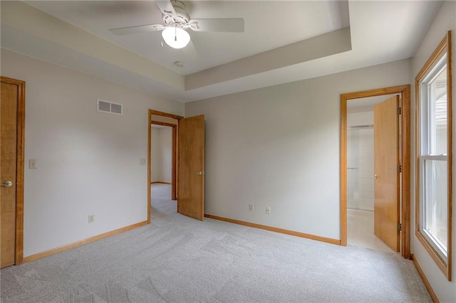 833 SW Harvest Dr, Grain Valley, MO 64029 - unfurnished bedroom featuring light colored carpet, baseboards, ensuite bath, and a tray ceiling