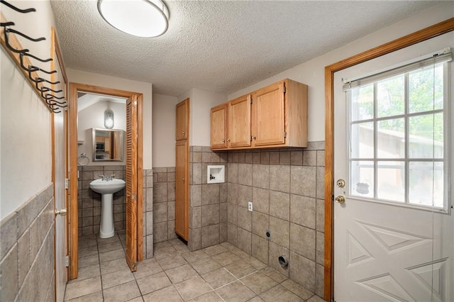11124 W 69th Ter, Shawnee, KS 66203 - washroom featuring tile walls, washer hookup, a textured ceiling, wainscoting, and light tile patterned floors