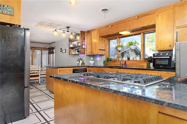 424 S Elm St, Ottawa, KS 66067 - kitchen featuring stainless steel appliances, a peninsula, a sink, dark stone counters, and brown cabinetry