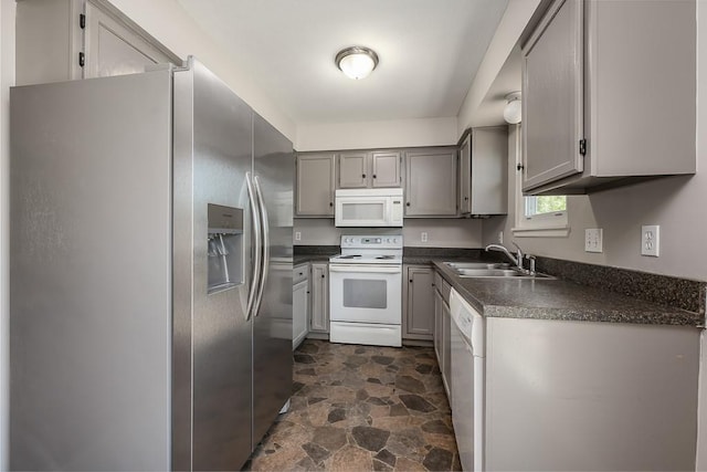 1180 Greenwood Pkwy, Tonganoxie, KS 66086 - kitchen featuring white appliances, a sink, dark countertops, dark stone finish floors, and gray cabinetry