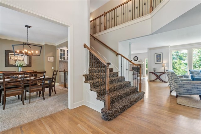 13897 W 140th St, Olathe, KS 66062 - stairway featuring wood finished floors, a chandelier, a high ceiling, crown molding, and baseboards