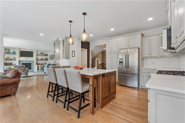13897 W 140th St, Olathe, KS 66062 - kitchen featuring stainless steel fridge with ice dispenser, light countertops, open floor plan, light wood finished floors, and recessed lighting