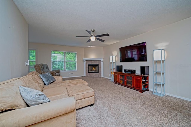 1604 S 105th Ter, Edwardsville, KS 66111 - carpeted living room featuring a ceiling fan, baseboards, a tiled fireplace, and a textured ceiling