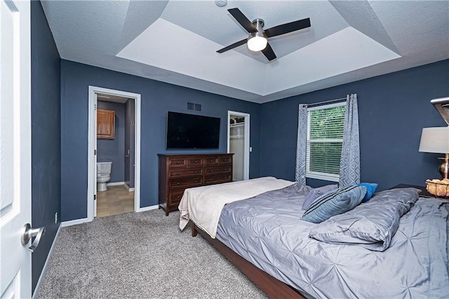 1604 S 105th Ter, Edwardsville, KS 66111 - carpeted bedroom featuring a tray ceiling, baseboards, ensuite bath, and ceiling fan