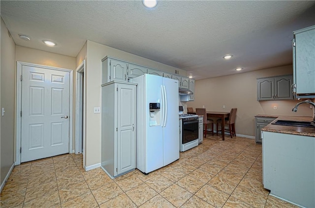 1604 S 105th Ter, Edwardsville, KS 66111 - kitchen featuring a sink, gas range oven, white fridge with ice dispenser, under cabinet range hood, and light tile patterned floors