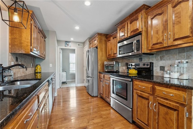 19708 E 11th Ter N, Independence, MO 64056 - kitchen with appliances with stainless steel finishes, a sink, brown cabinets, dark stone countertops, and baseboards