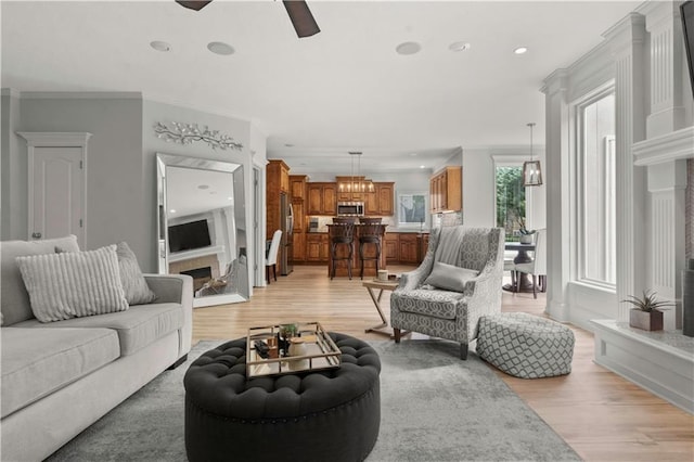 11412 S Lakecrest Dr, Olathe, KS 66061 - living room with light wood finished floors, ceiling fan, a fireplace with raised hearth, ornamental molding, and recessed lighting