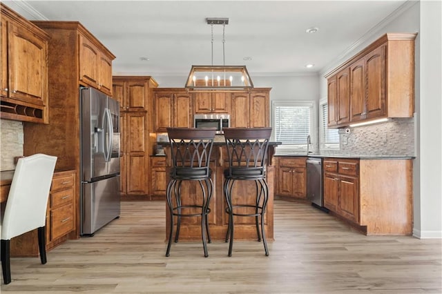 11412 S Lakecrest Dr, Olathe, KS 66061 - kitchen featuring stainless steel appliances, light wood-style flooring, a breakfast bar, brown cabinetry, and crown molding