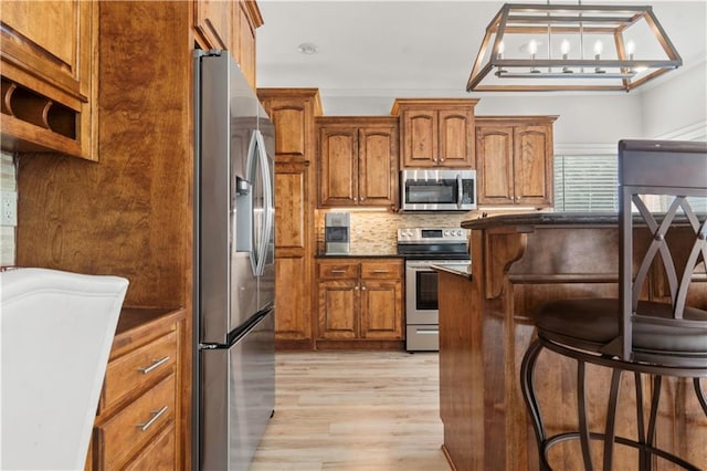 11412 S Lakecrest Dr, Olathe, KS 66061 - kitchen featuring stainless steel appliances, light wood finished floors, brown cabinetry, and a breakfast bar area