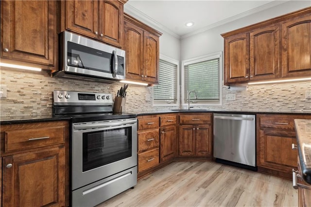 11412 S Lakecrest Dr, Olathe, KS 66061 - kitchen with appliances with stainless steel finishes, a sink, ornamental molding, dark countertops, and light wood-type flooring