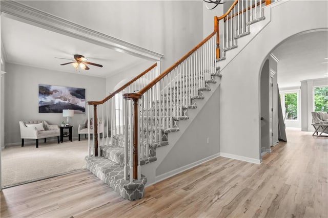 11412 S Lakecrest Dr, Olathe, KS 66061 - stairway with arched walkways, a ceiling fan, wood finished floors, baseboards, and ornamental molding