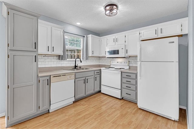 1413 SE Norwood Dr, Lees Summit, MO 64081 - kitchen featuring white appliances, a sink, a textured ceiling, light wood-style floors, and tasteful backsplash