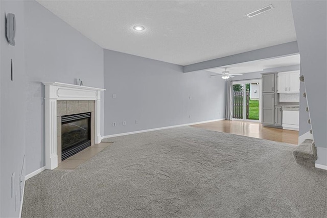 1413 SE Norwood Dr, Lees Summit, MO 64081 - unfurnished living room featuring light colored carpet, a tile fireplace, ceiling fan, a textured ceiling, and baseboards