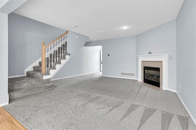 1413 SE Norwood Dr, Lees Summit, MO 64081 - unfurnished living room featuring stairs, baseboards, carpet, a tiled fireplace, and a textured ceiling