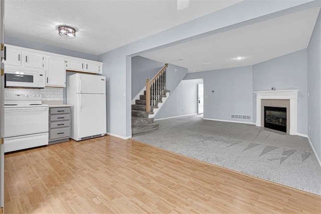 1413 SE Norwood Dr, Lees Summit, MO 64081 - kitchen with white appliances, baseboards, white cabinets, backsplash, and a glass covered fireplace