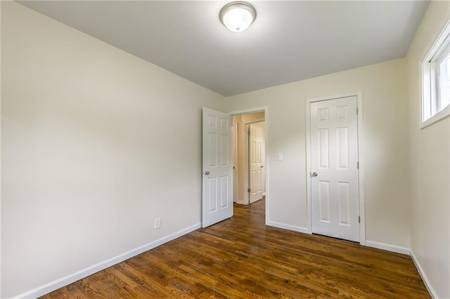 704 W 38th St N, Independence, MO 64052 - unfurnished bedroom with baseboards and dark wood-type flooring