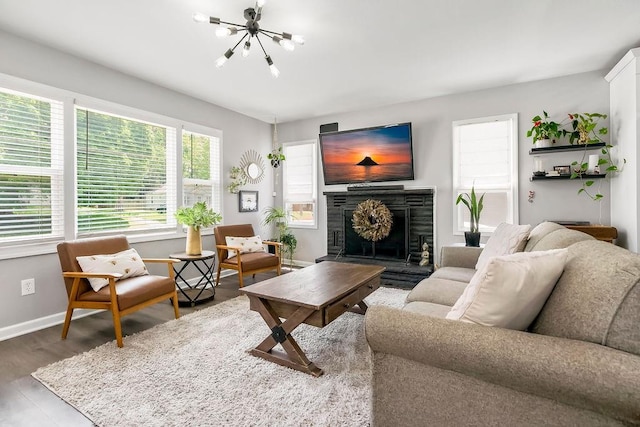 920 S Washington St, Independence, MO 64050 - living area with a chandelier, baseboards, a fireplace with raised hearth, and wood finished floors