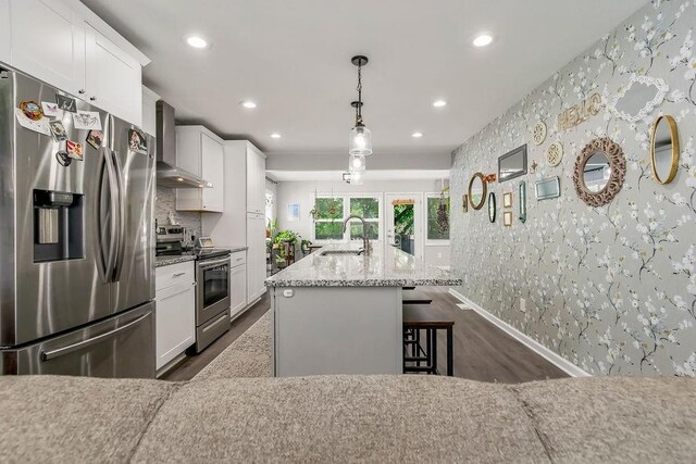 920 S Washington St, Independence, MO 64050 - kitchen featuring stainless steel appliances, wall chimney range hood, dark wood-style flooring, a sink, and wallpapered walls