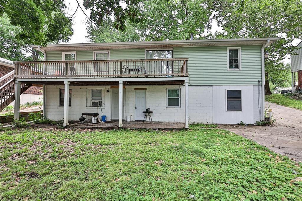 1316 N Main St, Independence, MO 64050 - back of property with a wooden deck, a lawn, stairway, and cooling unit