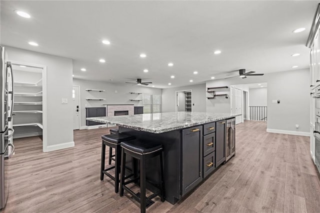 22617 155th St, Basehor, KS 66007 - kitchen with ceiling fan, a fireplace, a kitchen island, light wood-style floors, and recessed lighting