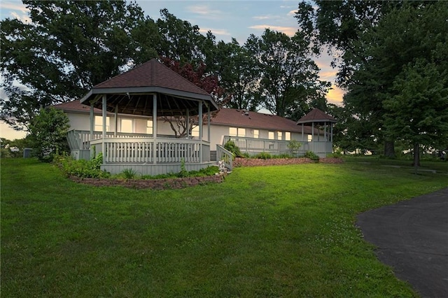 22617 155th St, Basehor, KS 66007 - back of house at dusk featuring a gazebo, a lawn, and stucco siding