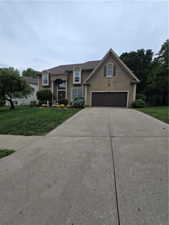 13810 W 53rd St, Shawnee, KS 66216 - view of front facade with driveway, a front lawn, and stucco siding