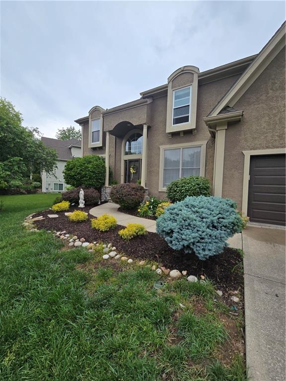 13810 W 53rd St, Shawnee, KS 66216 - view of front of property featuring stucco siding, a front lawn, and a garage