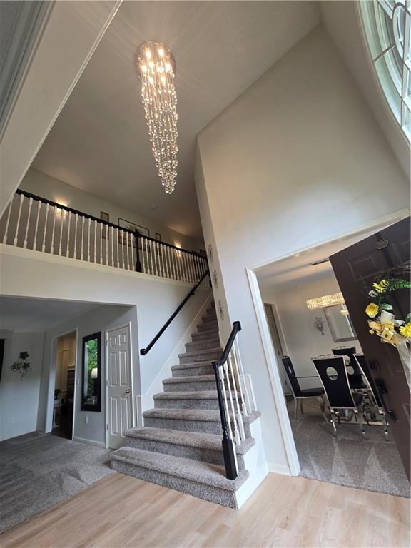 13810 W 53rd St, Shawnee, KS 66216 - stairs featuring a high ceiling, a chandelier, wood finished floors, and baseboards