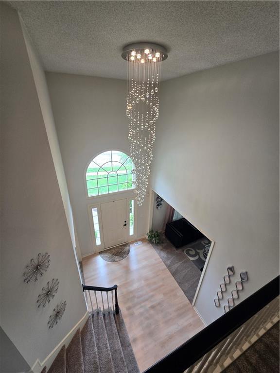13810 W 53rd St, Shawnee, KS 66216 - entrance foyer featuring wood finished floors, a textured ceiling, a towering ceiling, and baseboards
