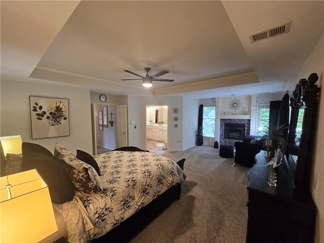 13810 W 53rd St, Shawnee, KS 66216 - carpeted bedroom featuring a tray ceiling, a glass covered fireplace, ensuite bathroom, baseboards, and a ceiling fan