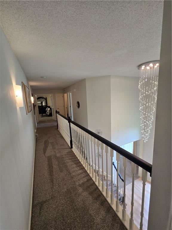 13810 W 53rd St, Shawnee, KS 66216 - hall with carpet floors, a chandelier, a textured ceiling, and an upstairs landing