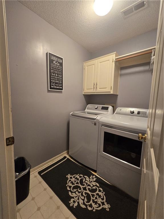 13810 W 53rd St, Shawnee, KS 66216 - laundry room with separate washer and dryer, cabinet space, a textured ceiling, tile patterned floors, and baseboards
