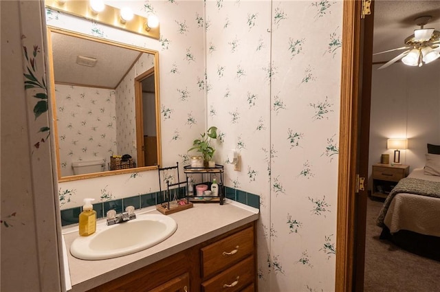 406 Cheyenne Ave, Coffeyville, KS 67337 - ensuite bathroom featuring vanity, ceiling fan, wallpapered walls, and toilet