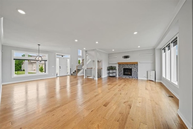 1709 SW Hightown Dr, Lees Summit, MO 64082 - unfurnished living room with light wood-style floors, radiator, a stone fireplace, crown molding, and stairway
