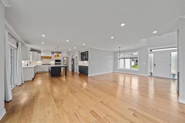 1709 SW Hightown Dr, Lees Summit, MO 64082 - unfurnished living room with crown molding, light wood-style flooring, recessed lighting, and a chandelier