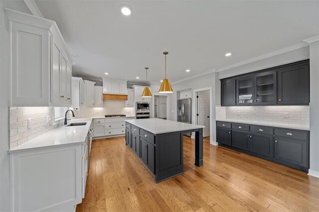 1709 SW Hightown Dr, Lees Summit, MO 64082 - kitchen with appliances with stainless steel finishes, a breakfast bar, a kitchen island, backsplash, and crown molding