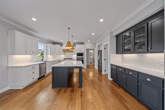 1709 SW Hightown Dr, Lees Summit, MO 64082 - kitchen featuring stainless steel appliances, white cabinets, decorative backsplash, a center island, and crown molding